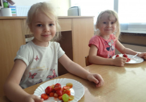 Dziewczynki próbują sałatkę owocową